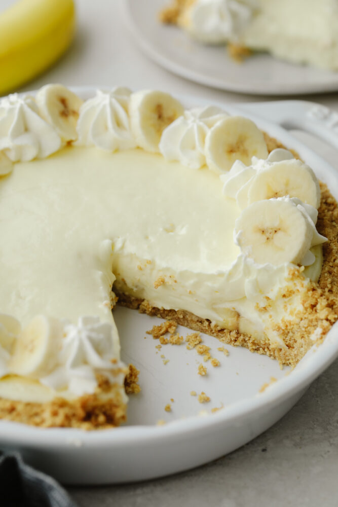 Banana cream cheesecake in a pie pan with a slice taken out. 