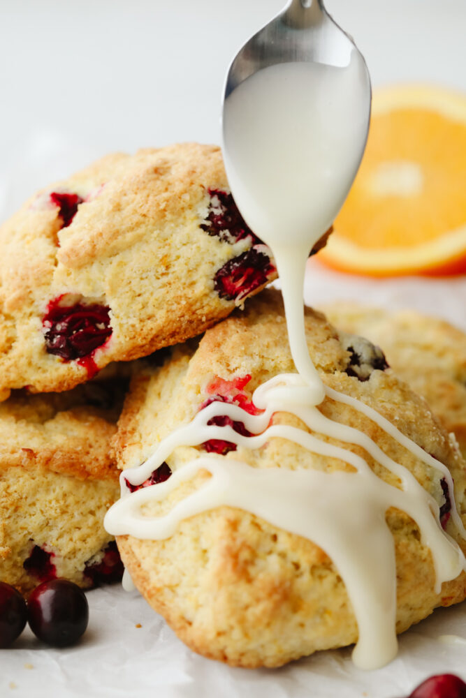 Orange glaze being drizzled on a scone. 