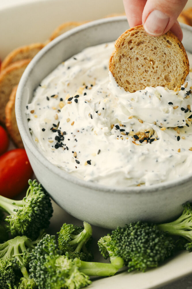 Bread being dipped into everything bagel dip. 