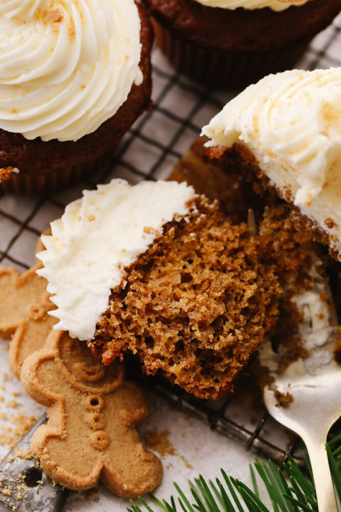 A gingerbread cupcake on a cooling rack being cut open with a fork. 