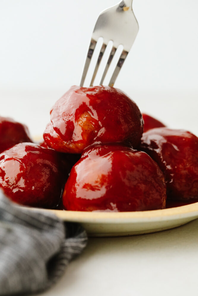 Closeup of ham balls, one being stuck with a fork.