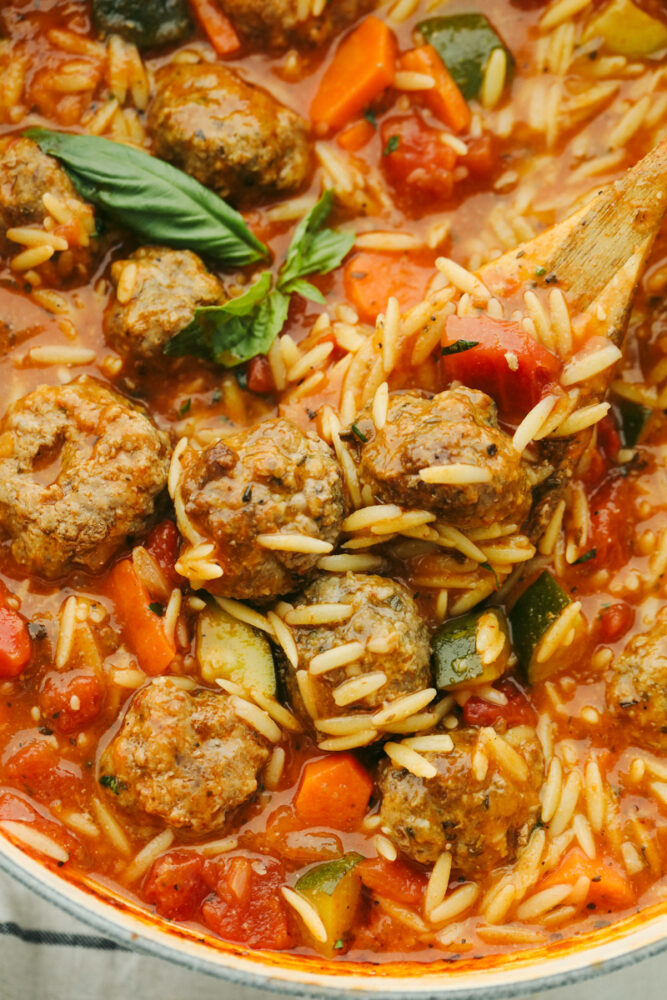 Meatball soup being dished out with a wooden spoon. 