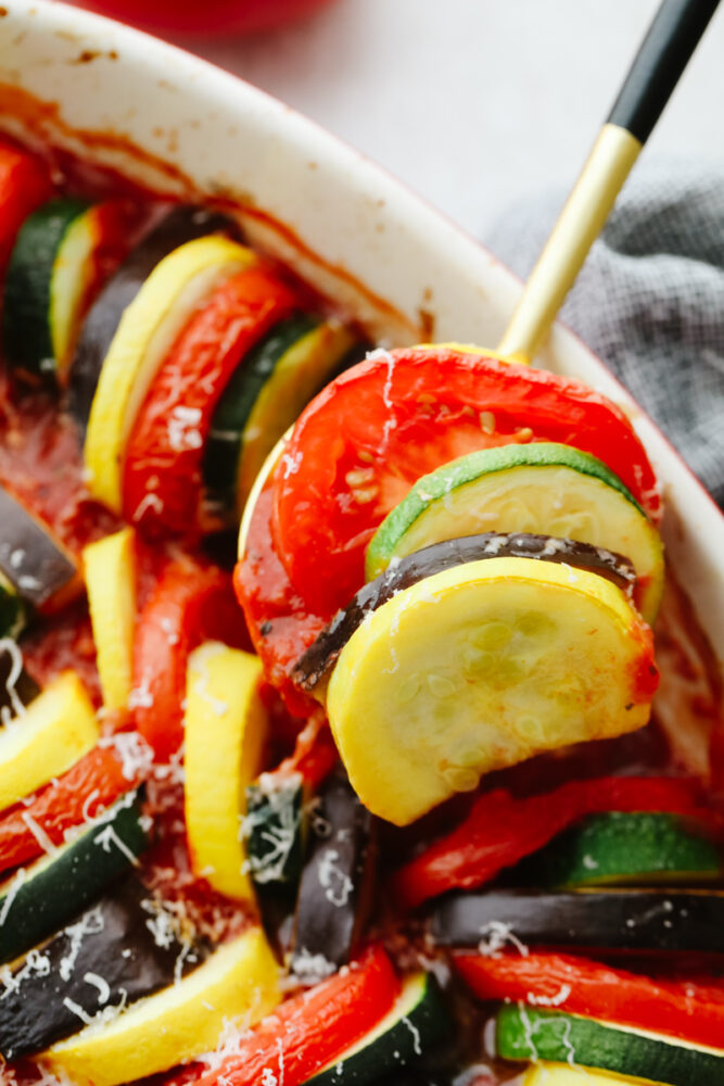 Cooked ratatouille being dished with a spoon. 