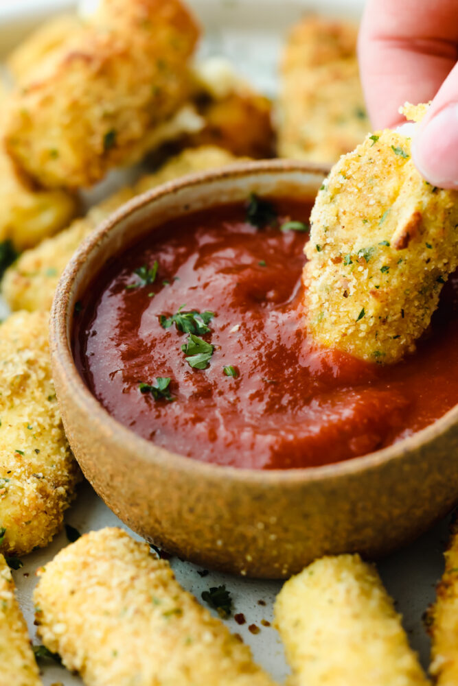 Dipping a mozzarella stick into marinara sauce.