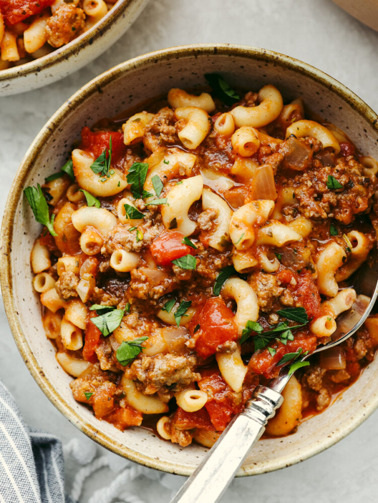 A bowl of American goulash with a silver spoon. 