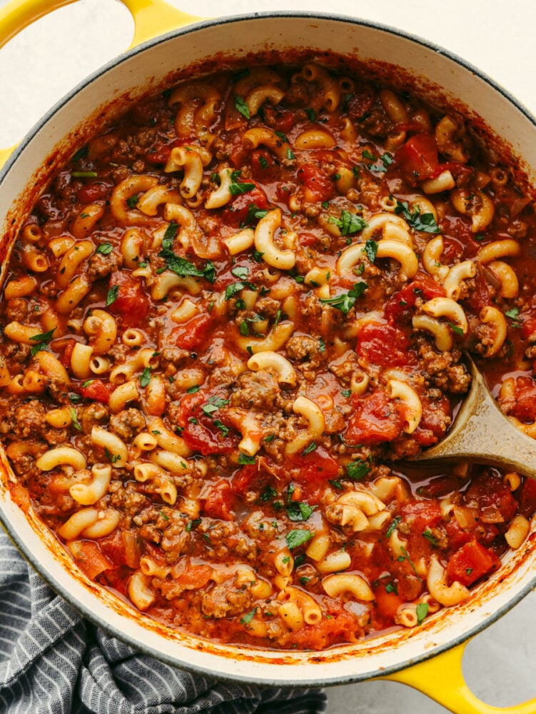 A pot of American goulash with a wooden spoon in it. 