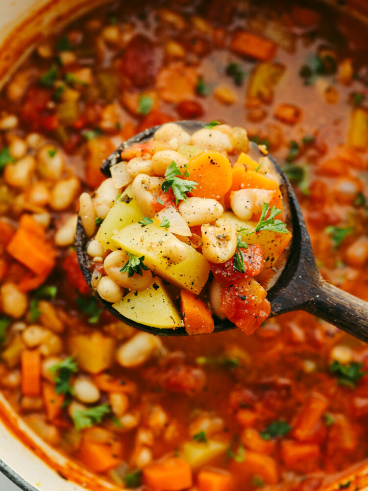 A wooden spoon filled with bean stew. 