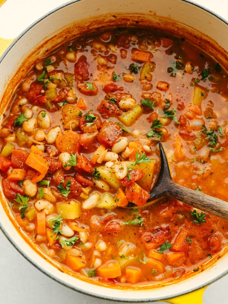 A pot filled with bean stew and a wooden serving spoon. 