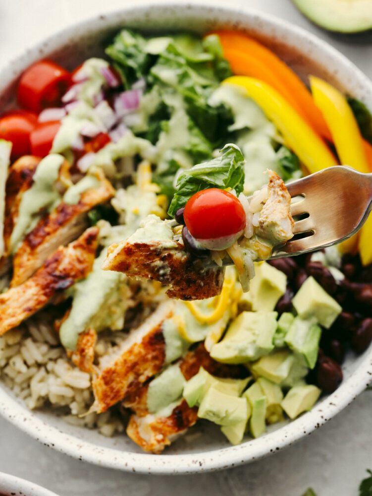 Taking a bite of chicken and vegetables with a fork.