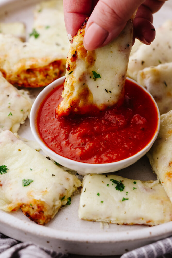 Dipping a breadstick in marinara sauce.