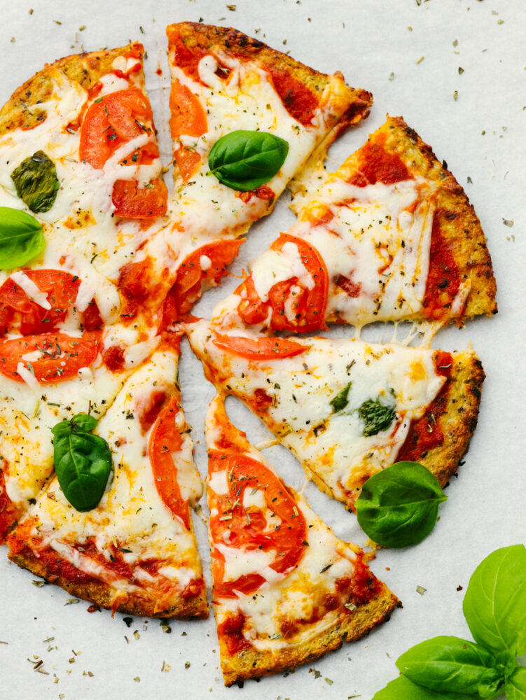 A pizza with tomatoes, basil and a cauliflower crust.