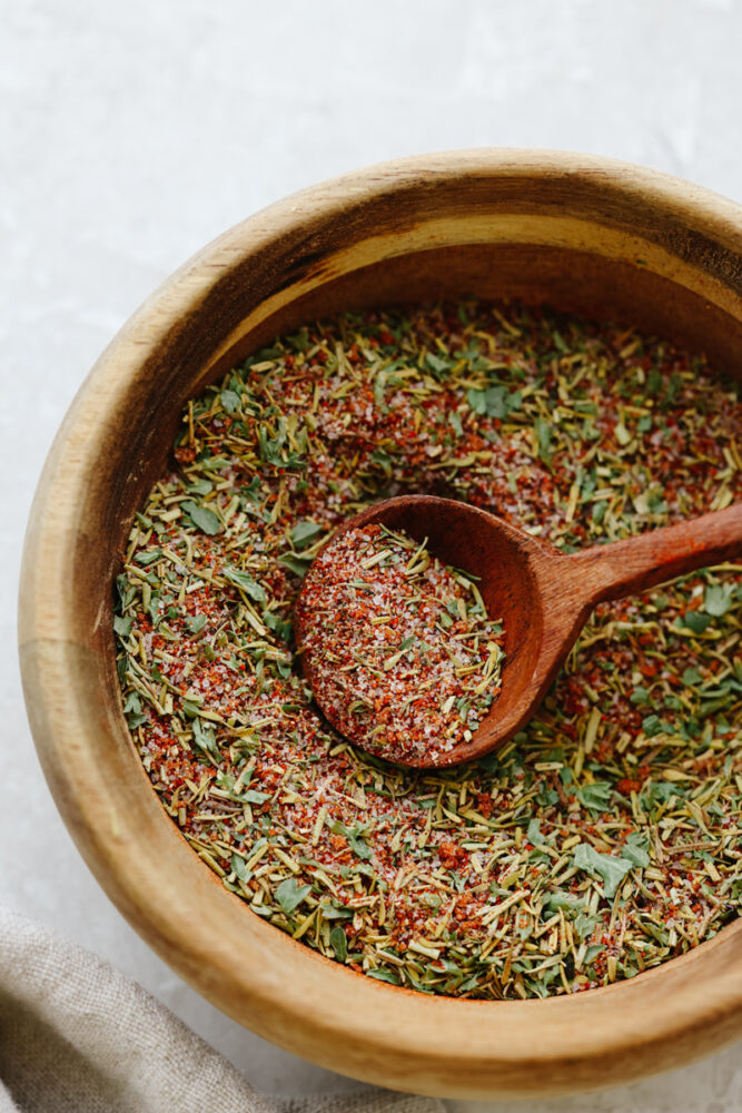 A wooden bowl filled with spices and a wooden spoon. 