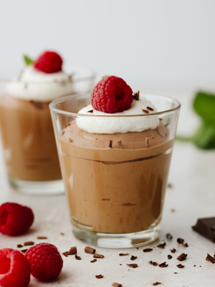 Chocolate mousse in a glass, topped with whipped cream and a raaspberry. 