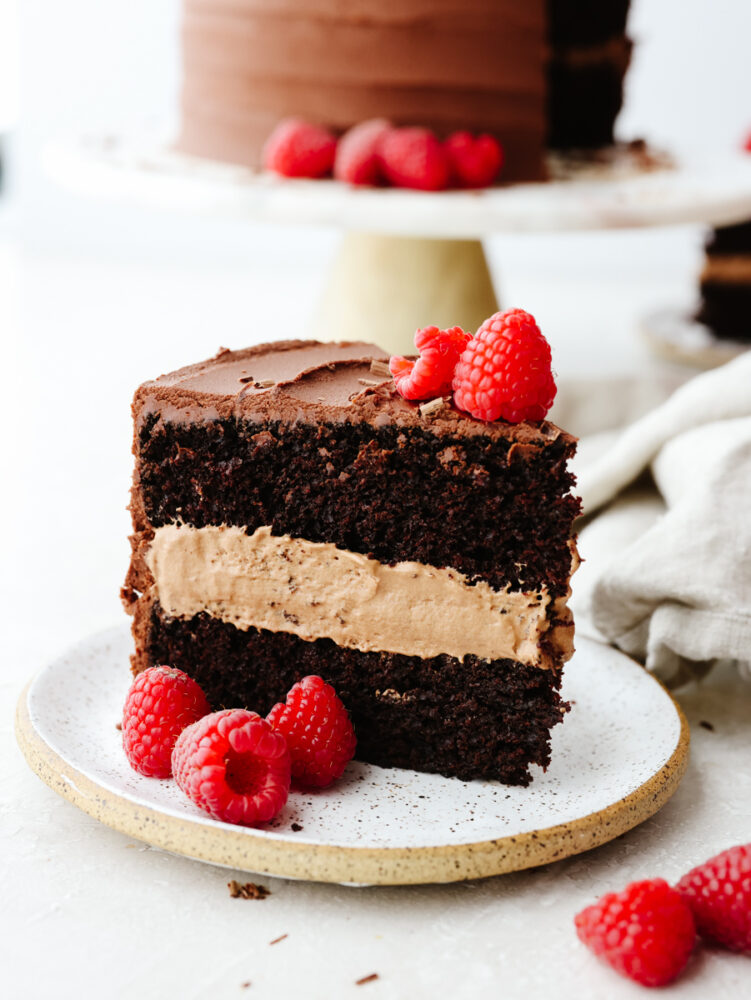 A slice of chocolate mousse cake with raspberries on a plate. 