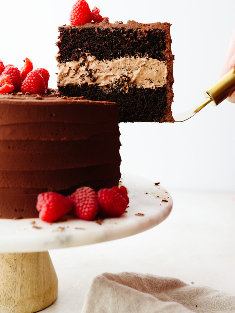 Chocolate mousse cake on a pedastal with a slice being taken out. 