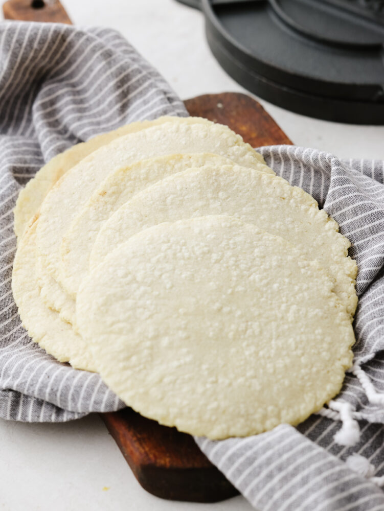 A stack of corn tortillas on a dish towel. 