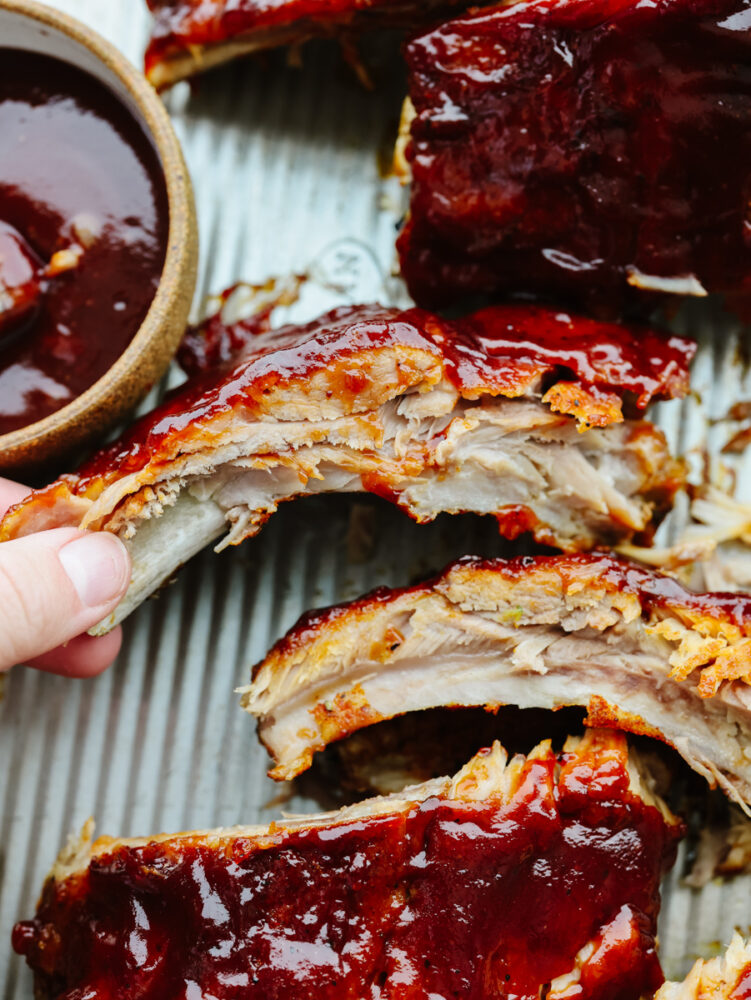 A hand picking up an instant pot rib to eat. 