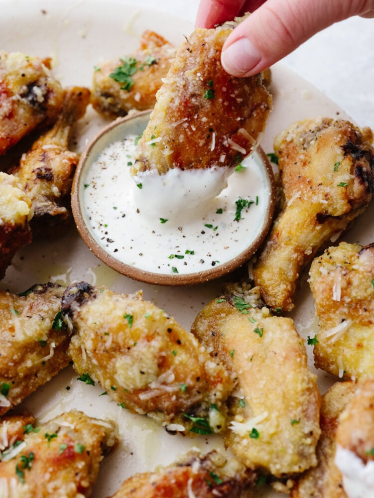 A parmesan garlic wing being dipped into ranch dressing. 