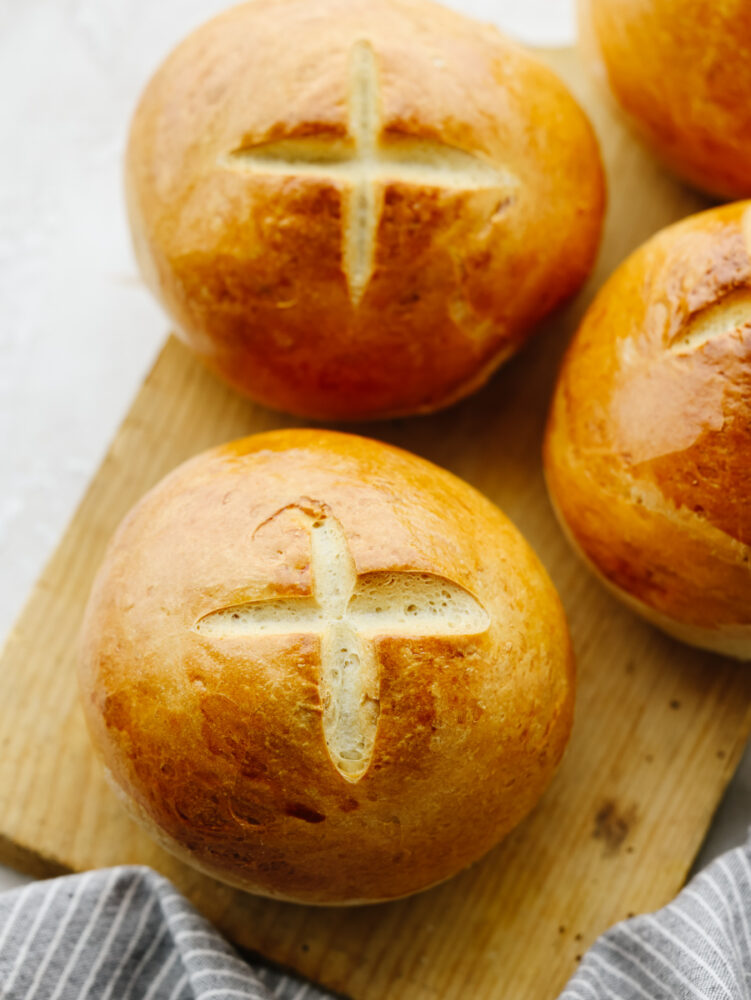 3 bread bowls on a wooden cutting board that are cooked and ready to eat. 