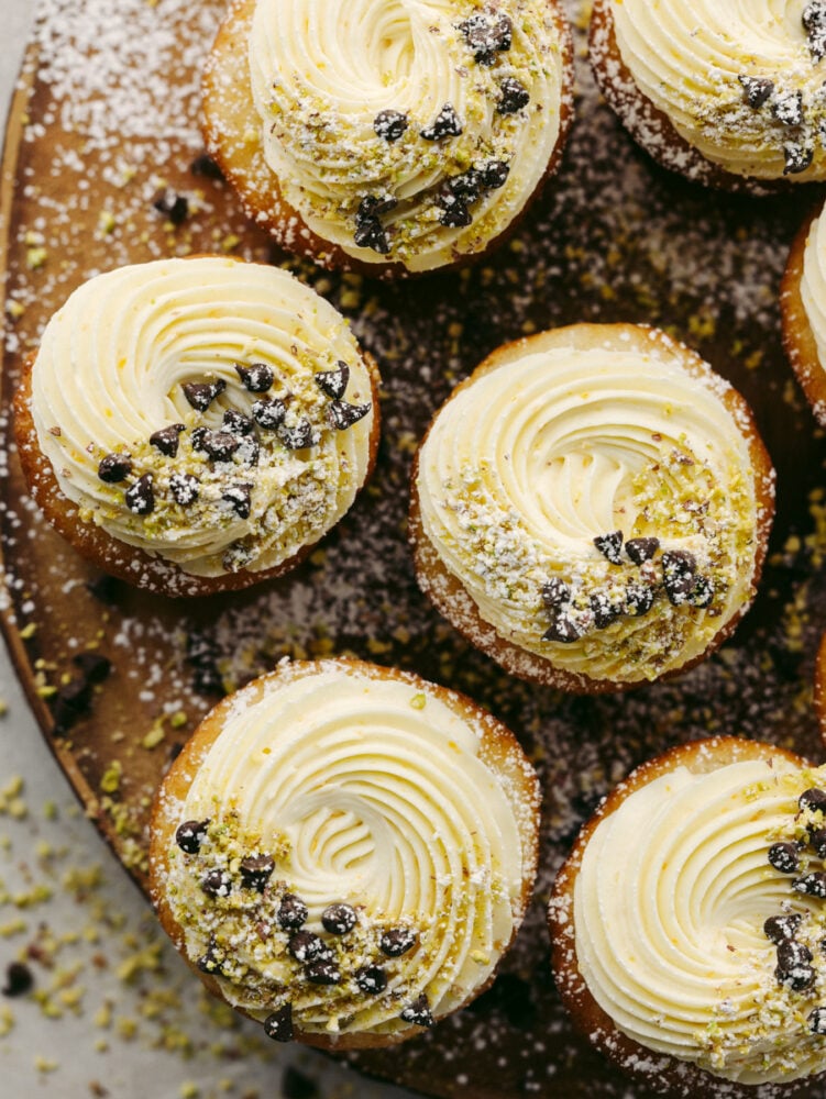 Top-down shot of cannoli cupcakes on a wooden board.