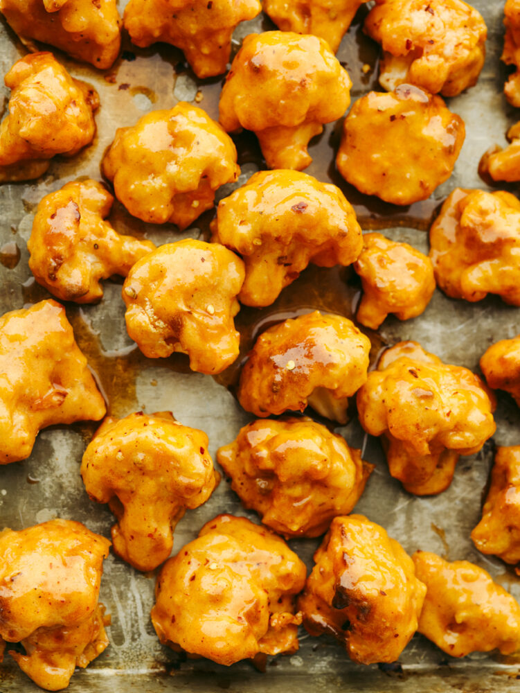 Baked cauliflower, coated in sauce on a baking sheet. 