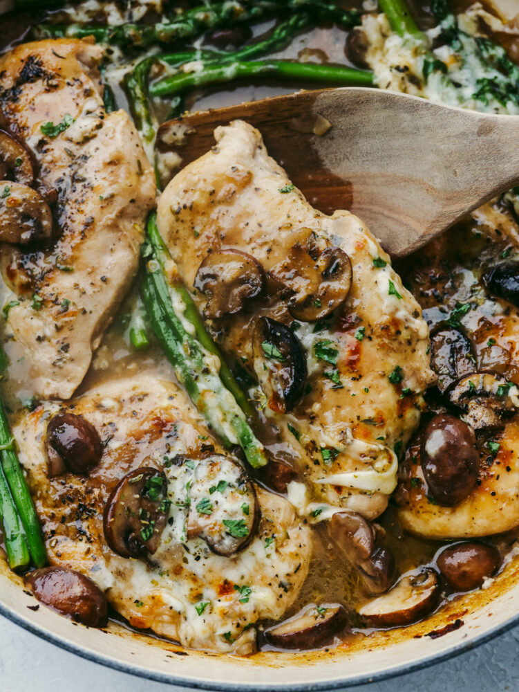 Closeup of scooping up a piece of chicken Madeira with a wooden spoon.