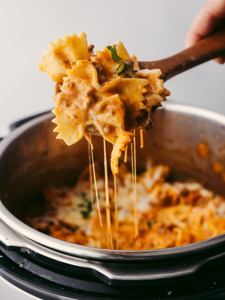 Scooping Instant Pot lasagna with a wooden spoon.