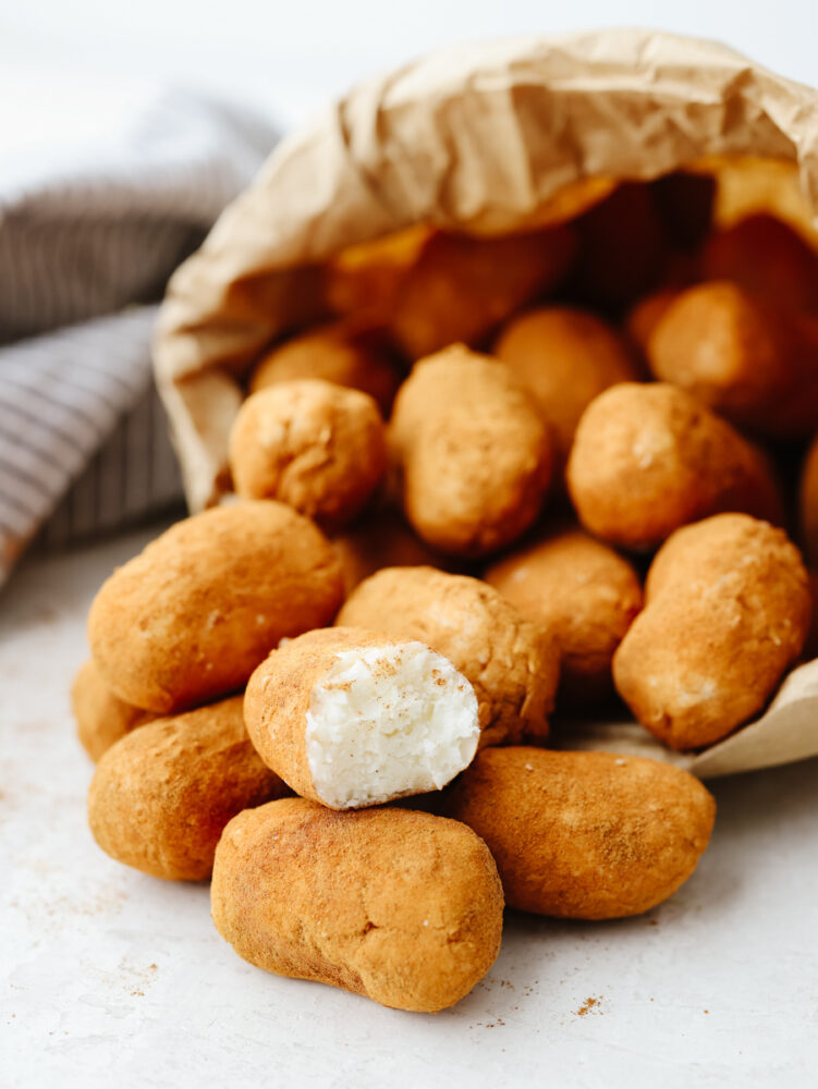 A paper bag on its side spilling out Irish potato candy. 