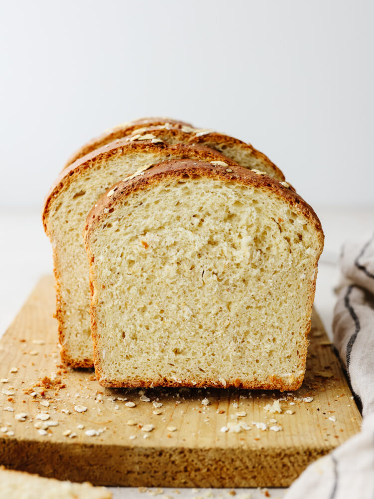 Sliced oatmeal bread on a wooden cutting board. 