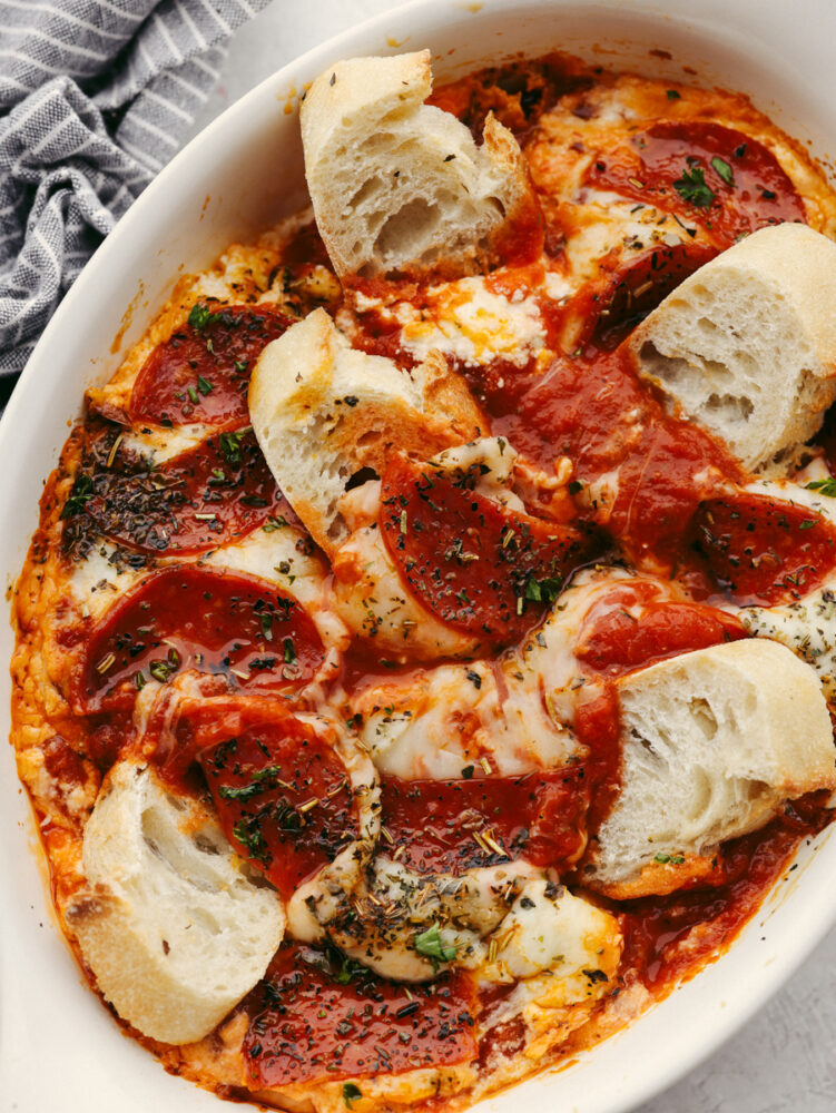 Bread being dipped into pepperoni pizza dip. 