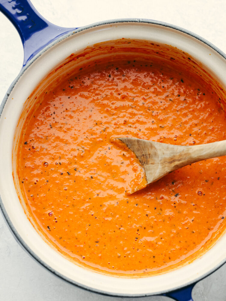 Top-down view of roasted red pepper sauce in a white and blue pan.