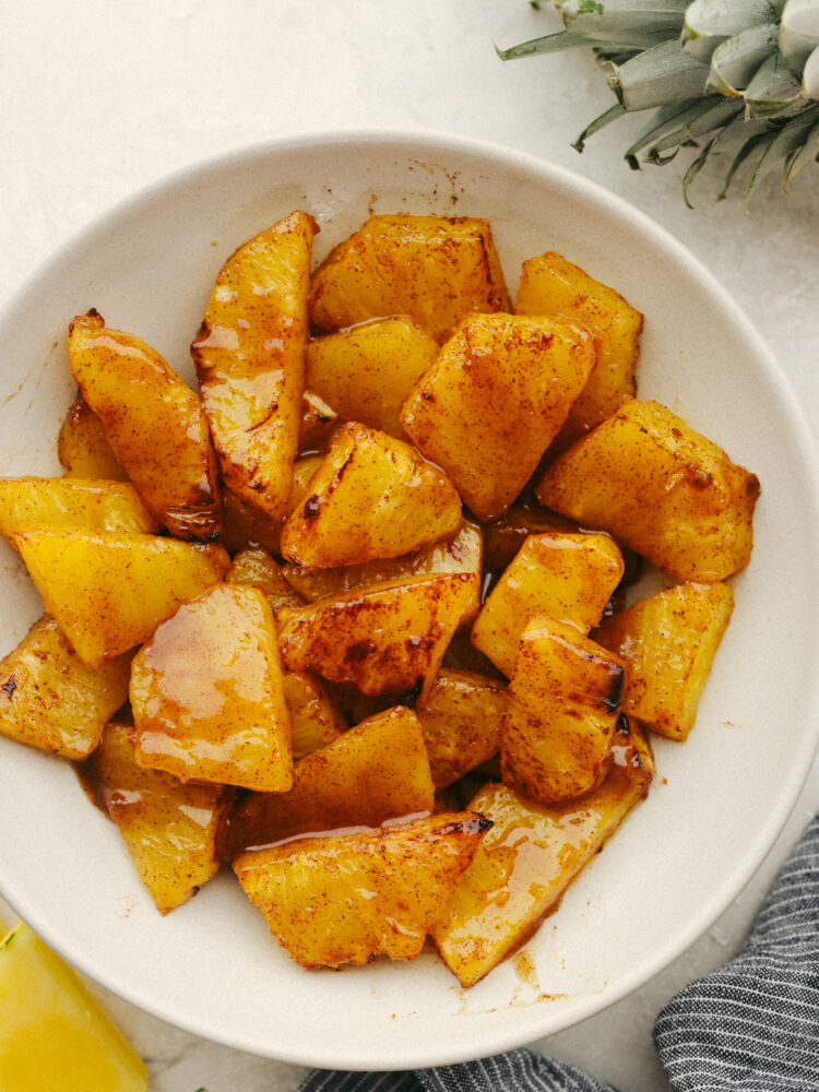 A bowl of sliced pineapple pieces with cartelized brown sugar. 