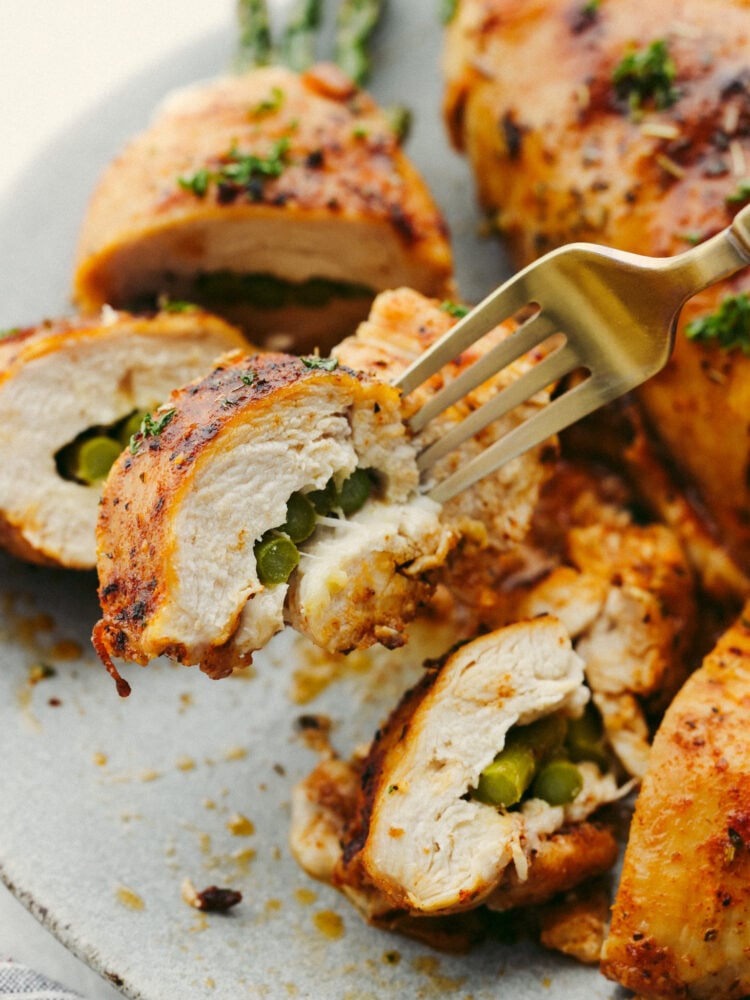 A chicken breast being cut into with a gold fork. 