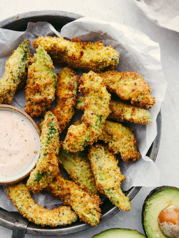 Air fryer avocado fries in a basket served with ranch.