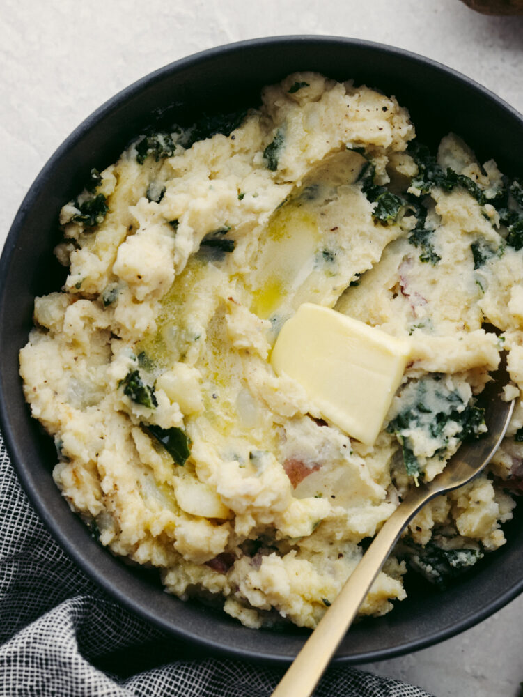 A bowl filled with colcannon and a spoon, ready to eat. 