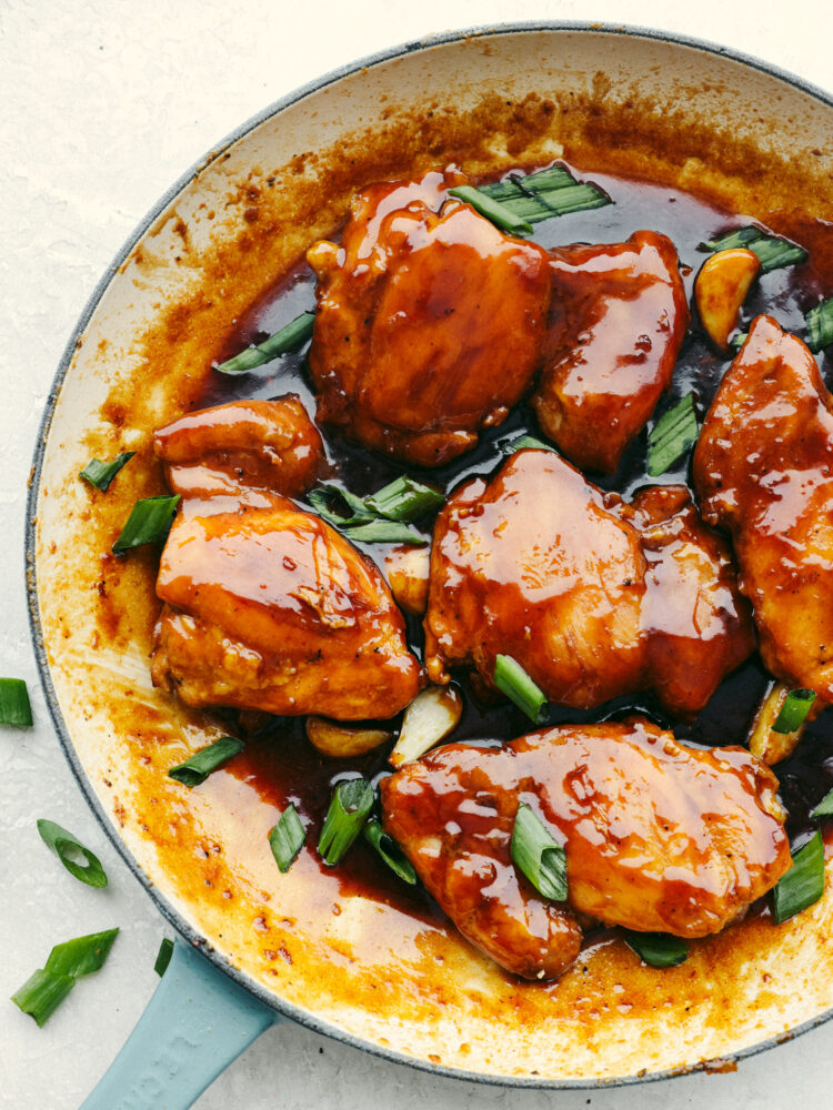 Caramel chicken garnished with scallions in a white and blue bowl.