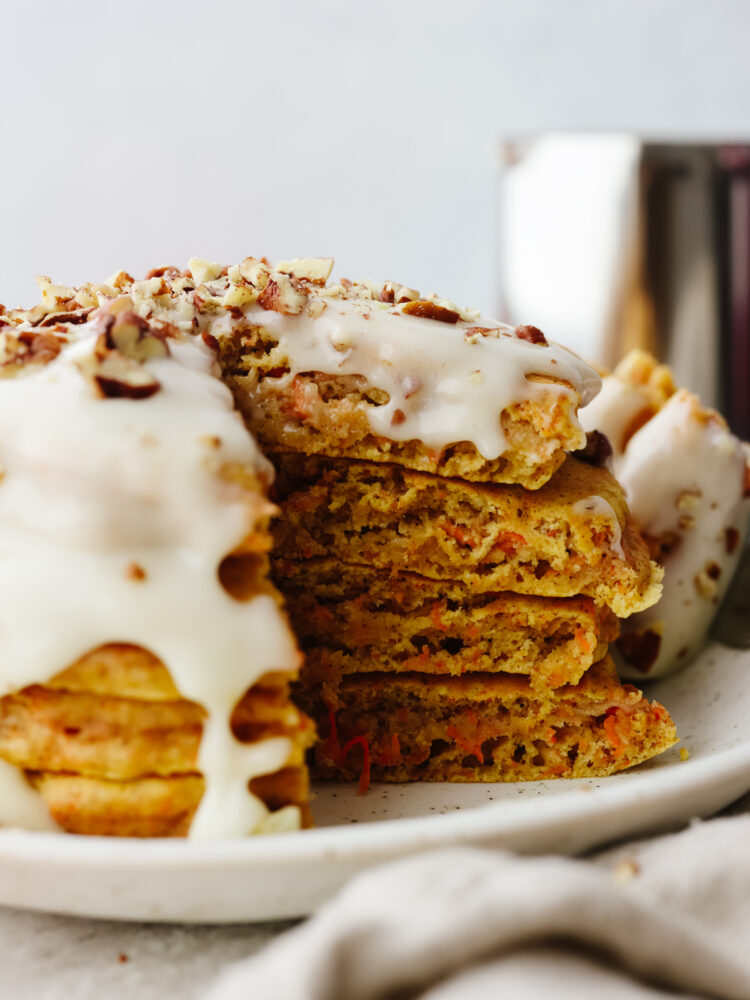 A stack of carrot cake pancakes with a triangle bite cut out of them 