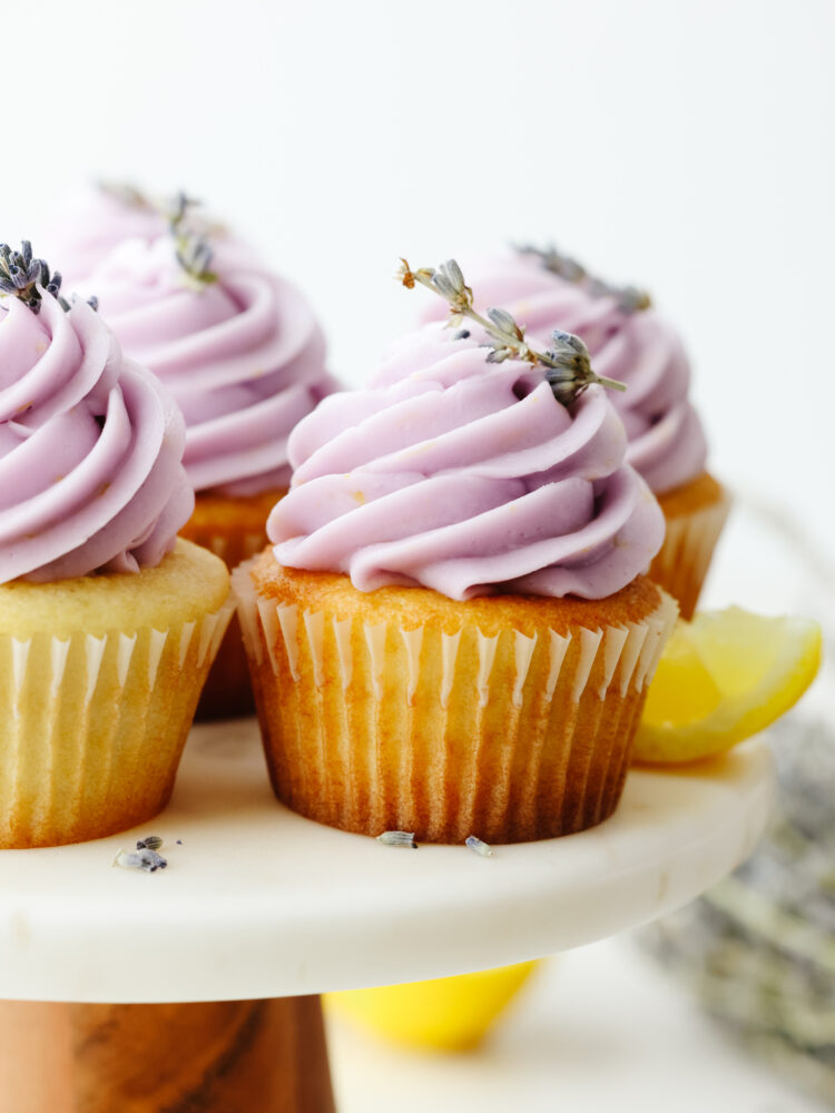 Lavender cupcakes on a cake stand with purple frosting and garnish with lavender buds. 