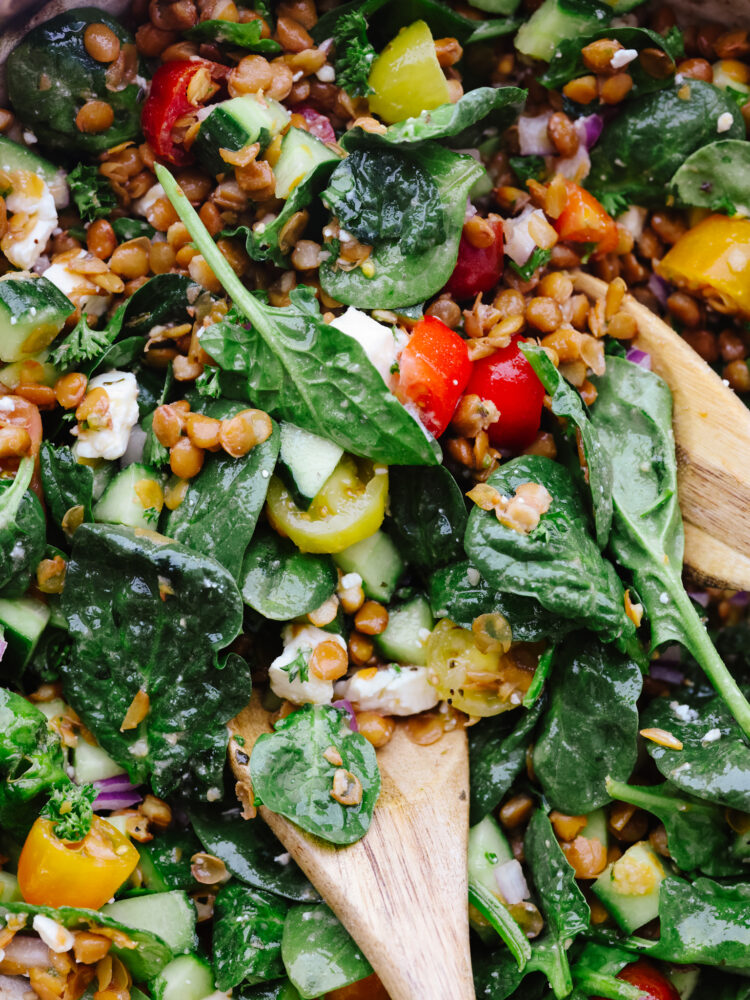 A close up of the salad with 2 wooden spoons in it. 