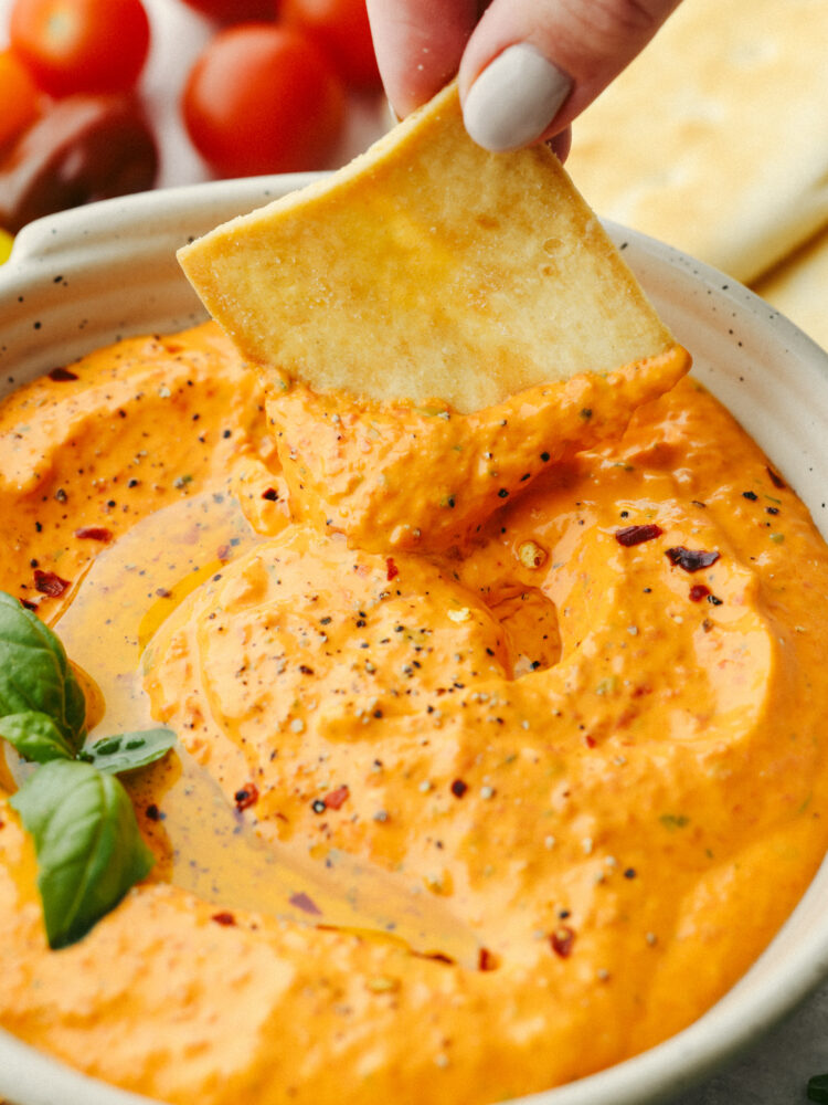 Closeup of a pita chip in red pepper dip.