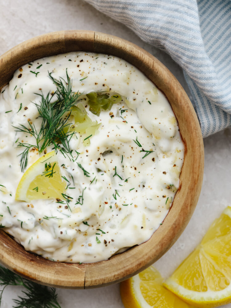 A wooden bowl filled with tartar sauce. 