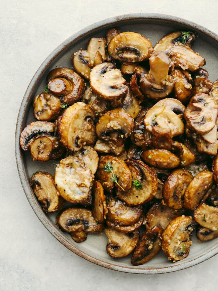 Top-down view of garlic parmesan mushrooms on a gray plate.