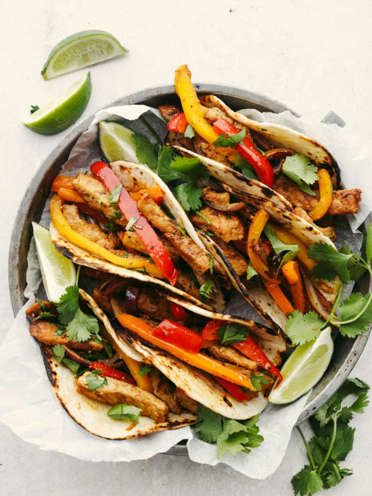 A pork fajita on a silver pie tin with parchment paper. 