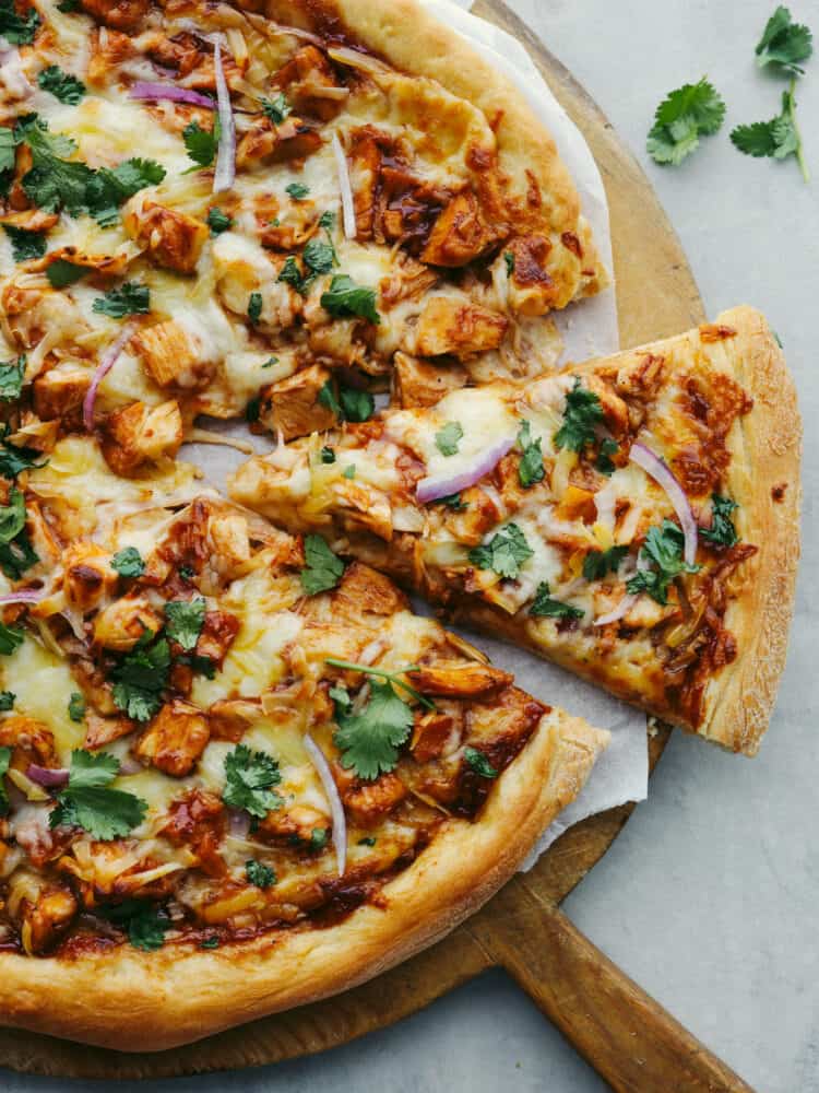 The top view of a BBQ Chicken pizza with a slice being dished out. 