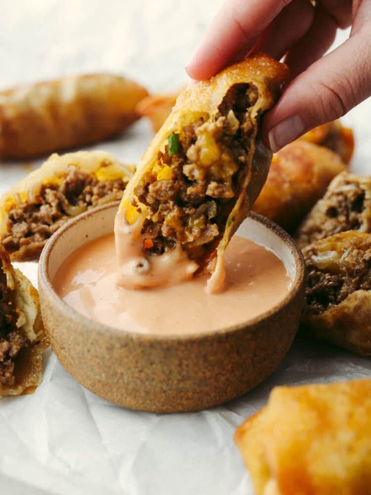 Dipping a cheeseburger eggroll in a creamy sauce.