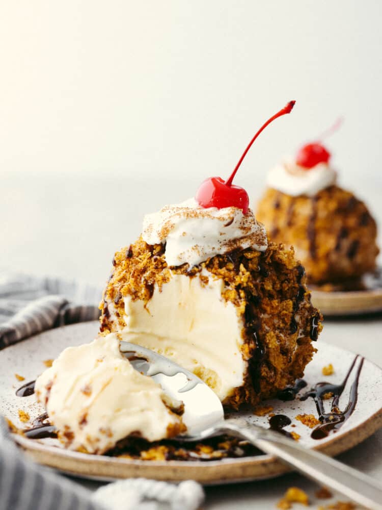 Easy fried ice cream molded into a circle, with a bite taken out of it revealing a creamy vanilla center.