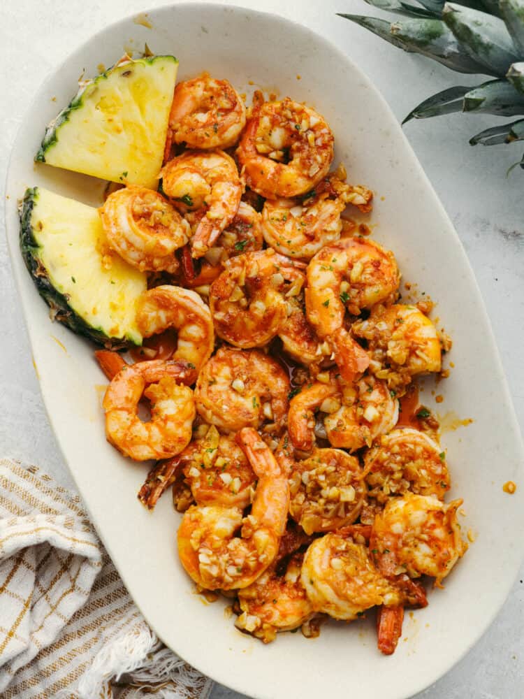 Top-down view of shrimp served with pineapple in a white plate.