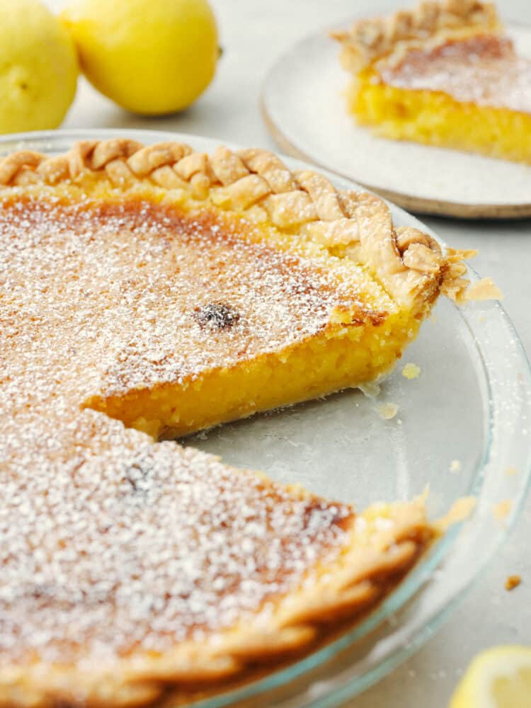 The side view of a lemon chess pie with a slice taken out of the glass pie pan. 