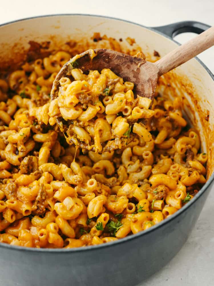 Hamburger helper being scooped out of a pan with a wooden spoon. 