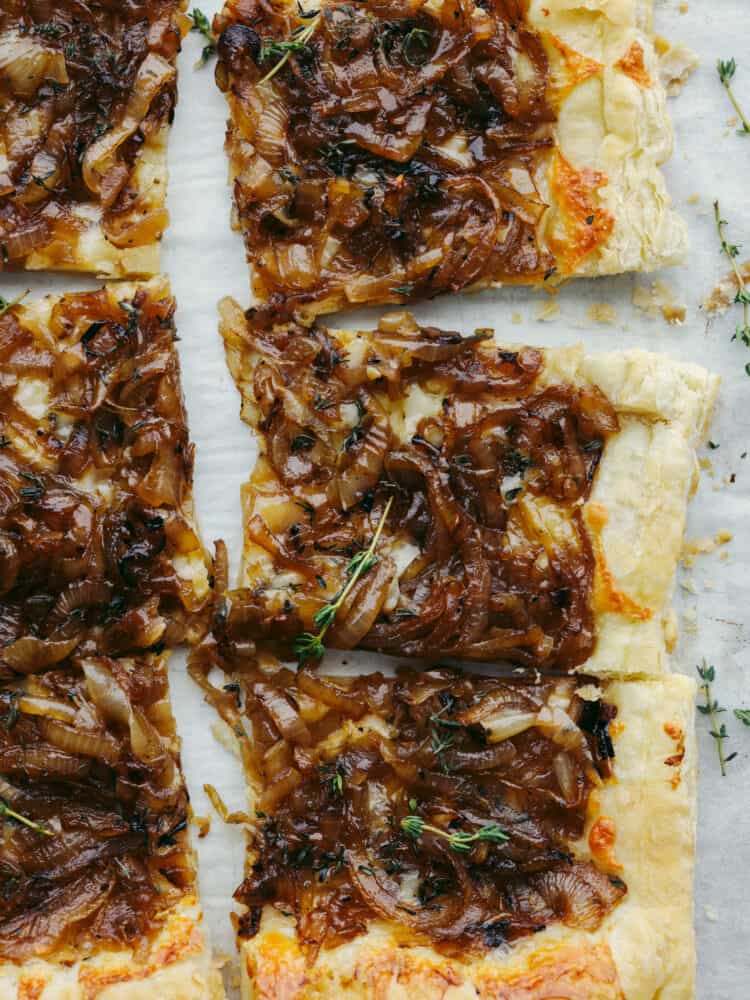 The top view of a cooked onion tart sliced into squares. 